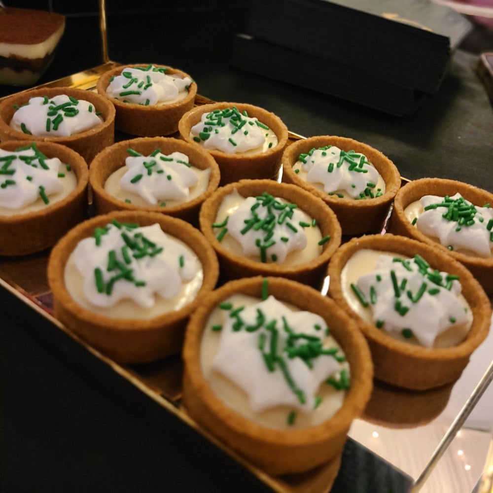 Mini pies with white filling and green sprinkles on a tray