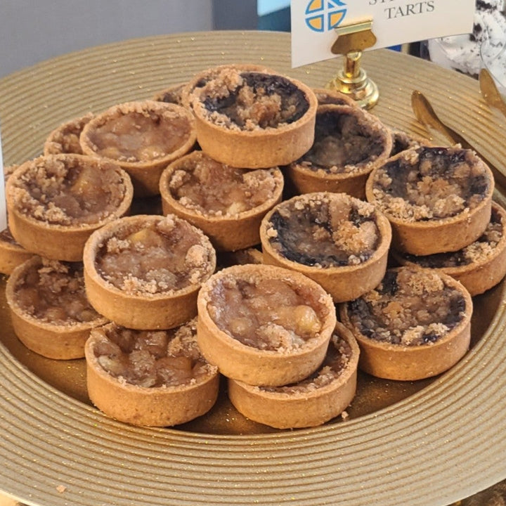 Apple and blueberry streusel tart featuring cinnamon-spiced apples, sweet blueberries, and a golden buttery crumble topping in a handcrafted pastry .