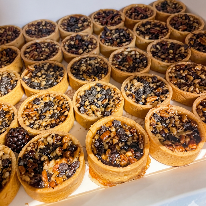 Mini 2-inch chocolate chip bourbon pecan tart with buttery pastry crust, rich bourbon pecan filling, and semi-sweet chocolate chips, handcrafted fresh by a luxury Las Vegas bakery.