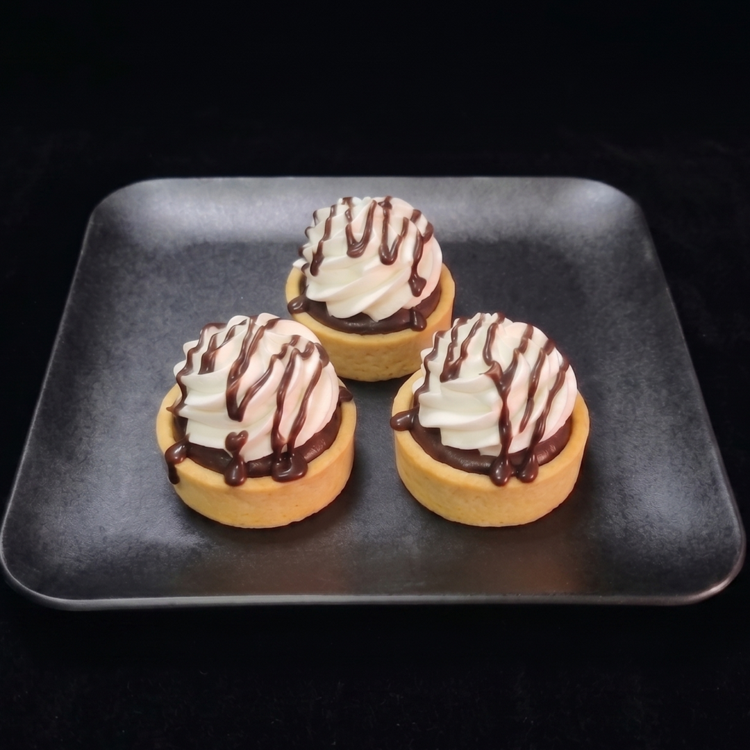Mini chocolate cream tartlets filled with rich chocolate cream and topped with non dairy whip, and chocolate ganache drizzle n a buttery pastry shell.