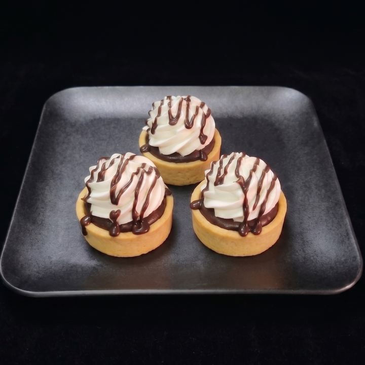 Mini chocolate cream tartlets filled with rich chocolate cream and topped with non dairy whip, and chocolate ganache drizzle n a buttery pastry shell.