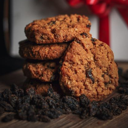 Stack of cookies with raisins on a wooden surface, red bow in the background