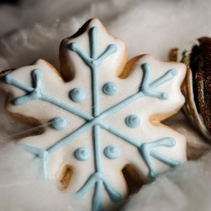 Snowflake-shaped cookie with blue icing on a white surface