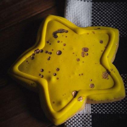 Yellow star-shaped object with small beads on a checkered fabric background