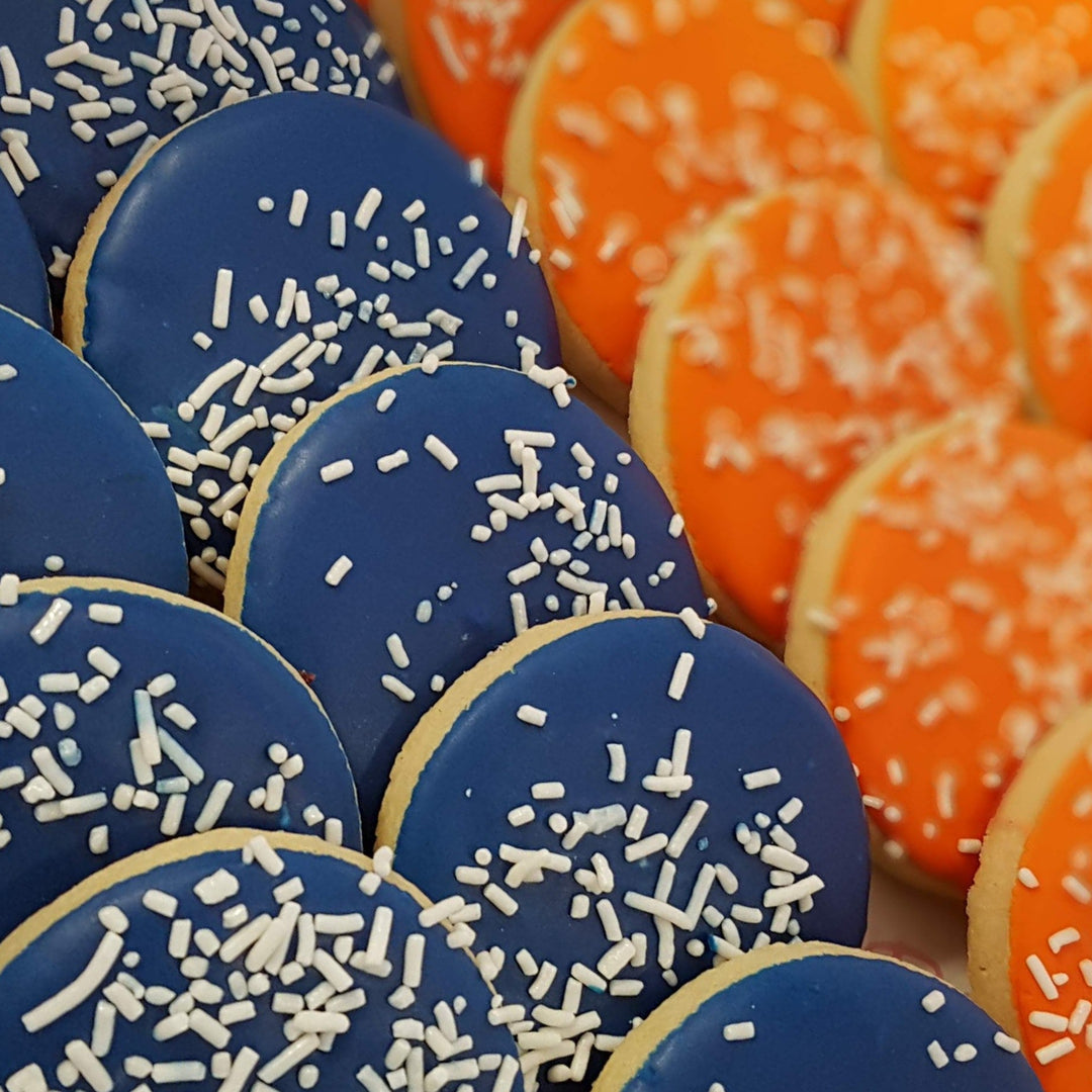 Blue and orange cookies with white sprinkles on a wooden surface