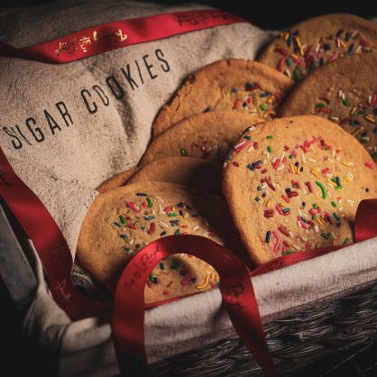 Decorative basket of sugar cookies with sprinkles on a textured surface.