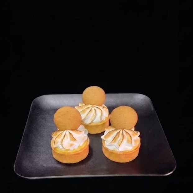 3 small banana cream pie tarts desserts with meringue on a black square plate. Banana cream tart filled with vanilla pudding and fresh sliced bananas, topped with toasted meringue and a Nilla wafer in a buttery pastry shell.