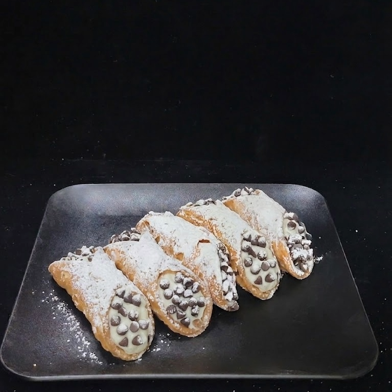 Mini cannoli with crisp pastry shells filled with sweet ricotta cream and finished with chocolate chips, handcrafted fresh for dessert tables and events.
