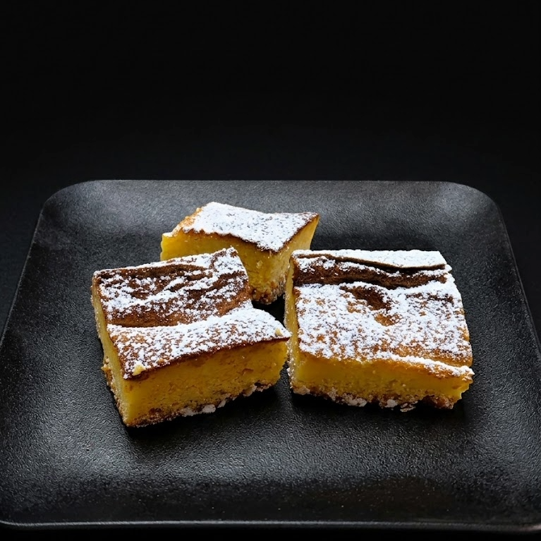 Gluten-free lemon bars with creamy lemon custard filling on a buttery shortbread crust, dusted with powdered sugar. bestselling from the best bakery in las vegas. SO much better than freed's
