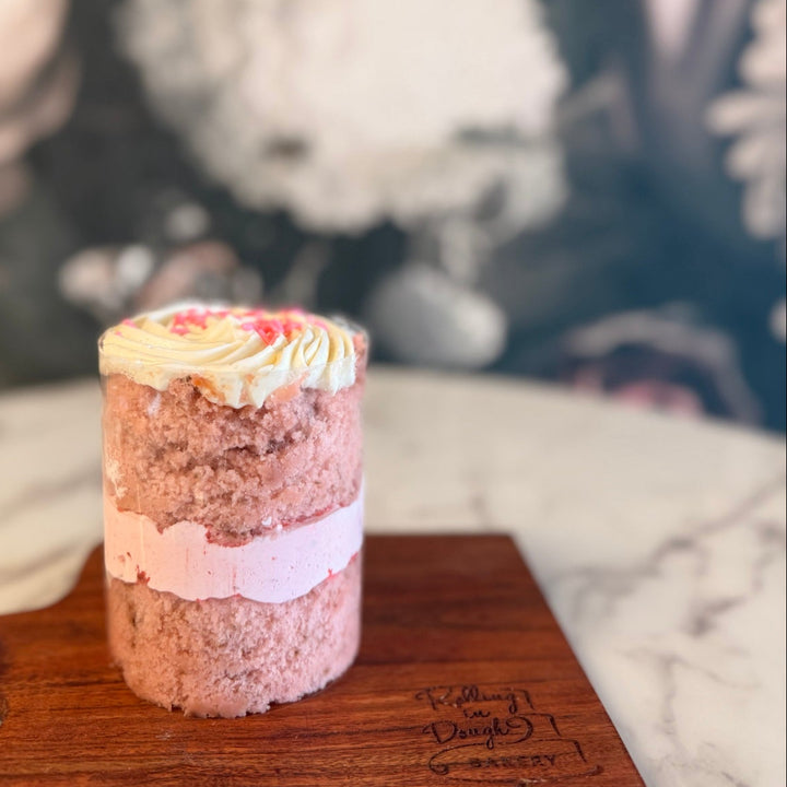 Small layered cake on a wooden board with a blurred floral background, strawberry cake with strawberry mousse