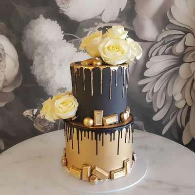 Our genuine 24 Carat gold painted on chocolate pieces and drips. Seasonal roses delicately arranged on the black fondant covered cake. Gold painted chocolate elements selected for size and balance then artfully arranged, creating a luxurious surprise for someone truly magnificent.